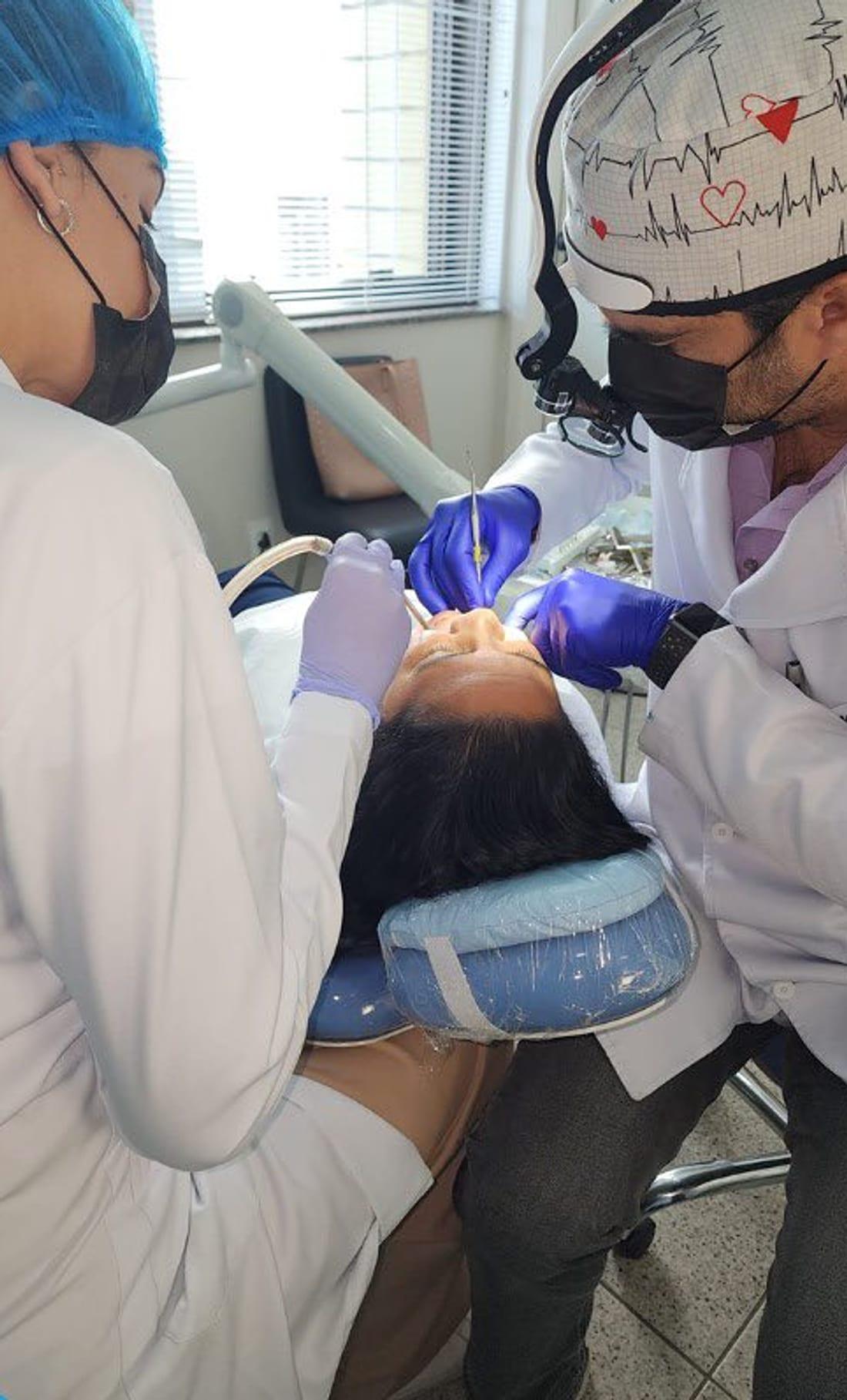 Dupla de profissionais da J & R Odontologia atendendo uma paciente na cadeira